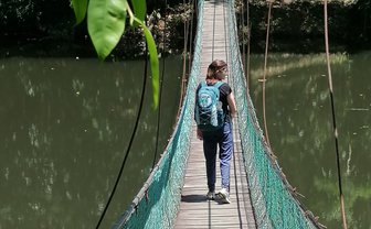 Frau geht über eine Hängebrücke, die einen See im Sepilok Rainforest Discovery Centre überspannt – Malaysia & Borneo Reise mit Kindern