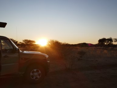 Ein Jeep steht vor dem Sonnenuntergang - Namibia mit Jugendlichen