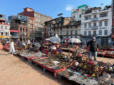 Bunte Stände mit handgefertigten Souvenirs und Kunsthandwerk füllen den Platz in Kathmandu, während Menschen stöbern.