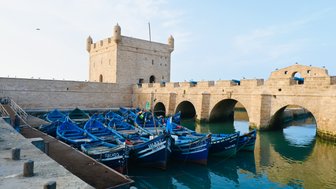 Bunte Boote schwimmen ruhig im Wasser des Hafens von Essaouira – Marokko Familienreise