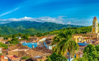 Blick auf die farbenfrohen Häuser von Trinidad, umgeben von üppigen Bergen und einem strahlend blauen Himmel.