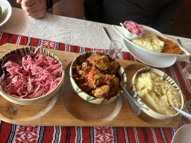 Ein rustikales Essen mit buntem Rotkohl, zartem Fleisch und cremigem Püree auf einem Holzbrett serviert.