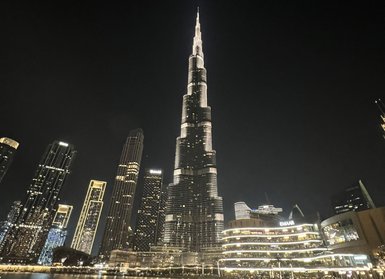 Der Burj Khalifa erhebt sich majestätisch über die beleuchtete Skyline von Dubai bei Nacht, umgeben von glitzerndem Wasser.