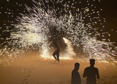 Ein Mensch tanzt im Dunkeln, während Funken in einem spektakulären Lichtspiel um ihn herumwirbeln.