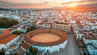 Die Arena von Ronda erhebt sich majestätisch über die Stadt, während die Sonne hinter den Bergen untergeht.