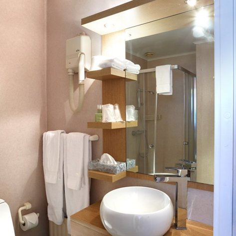 Ein modernes Badezimmer mit einem eleganten Waschbecken und Holzregalen, die Pflegeprodukte und Handtücher präsentieren.