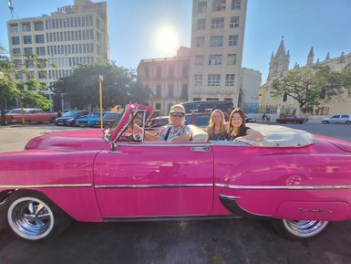 Drei Frauen sitzen in einem pinken Oldtimer-Cabrio in Havanna - Kuba mit Kindern