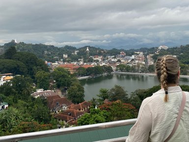 Teenagerin steht auf einem Aussichtspunkt und blickt über die Stadt Kandy – Sri Lanka Reise mit Kindern