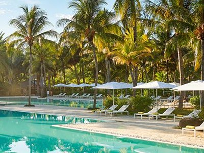 Ein glitzernder Pool umgeben von üppigen Palmen und Sonnenliegen, ideal für entspannende Tage in der Sonne.