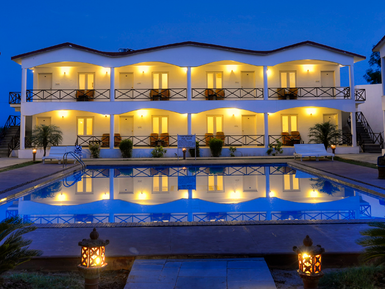 Ein elegantes Resort mit beleuchteten Zimmern spiegelt sich im ruhigen Pool bei Dämmerung wider.