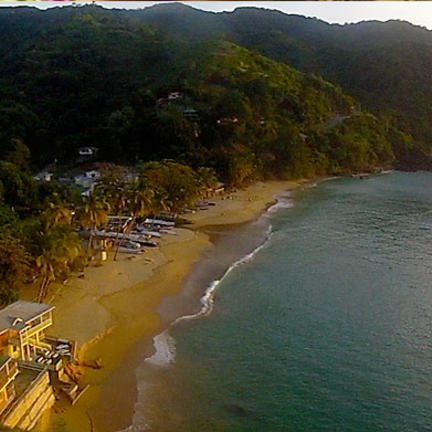 Eine malerische Küstenlandschaft mit sanften Hügeln, die sich über einen ruhigen Strand erstrecken, während Boote im Wasser schaukeln.