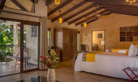 Ein stilvolles Hotelzimmer mit zwei Betten, einem großen Fenster und Blick auf die grüne Natur draußen.