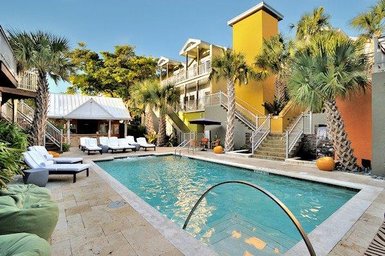 Ein einladender Poolbereich mit Liegen, umgeben von Palmen und bunten Gebäuden in Florida, ideal für Entspannung.