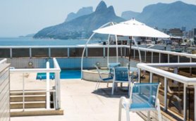 Auf der Terrasse des Atlantis Copacabana Hotels steht ein kleiner Pool mit Blick auf die Küste und die umliegenden Berge.