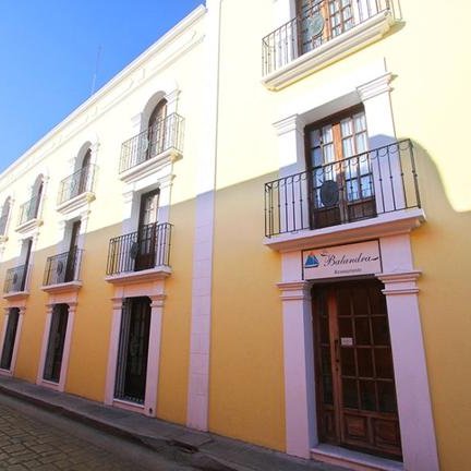 Eine gelbe Gebäudeansicht mit mehreren Fenstern und Balkonen, die eine einladende Atmosphäre ausstrahlt.