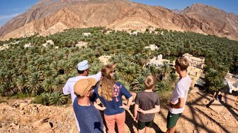 Einheimischer führt eine Familie durch das traditionelle Lehmdorf Birkat Al Mauz – Oman Reise mit Kindern