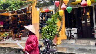 Frau trägt traditionellen vietnamesischen Hut bei Regen – Vietnam mit Kindern
