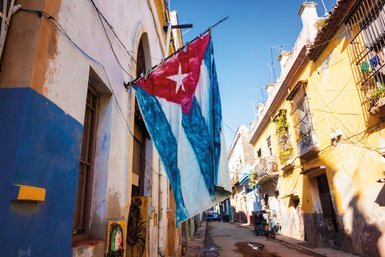 Eine große kubanische Flagge weht an einem Gebäude in einer Straße von Havanna