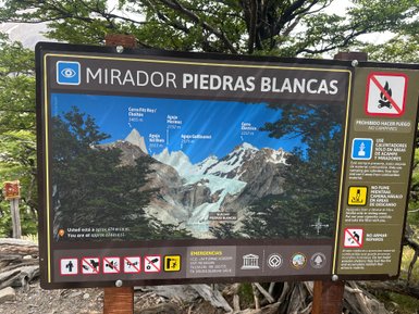Ein Informationsschild zeigt die beeindruckenden Gipfel des Cerro Fitz Roy und Cerro Mermoz in der patagonischen Landschaft.