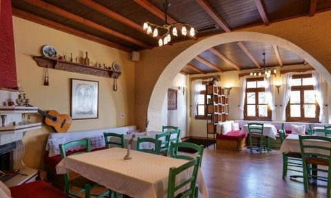 Ein einladendes Restaurant mit Holztischen und grünen Stühlen, umgeben von warmem Licht und traditioneller Dekoration.
