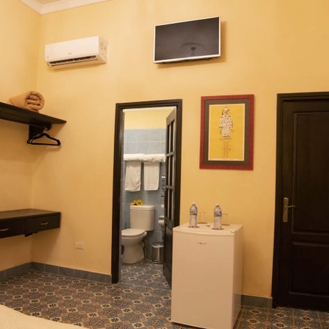 Ein helles Badezimmer mit gelben Wänden, einem großen Spiegel und einem modernen Fernseher an der Wand.