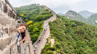 Teenager grüßt von der Großen Mauer mit weitem Blick auf die Landschaft Chinas – China Reise mit Kindern