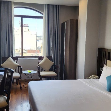 Ein modernes Hotelzimmer mit einem großen Fenster, das Tageslicht hereinlässt und einen Blick auf die Stadt bietet.
