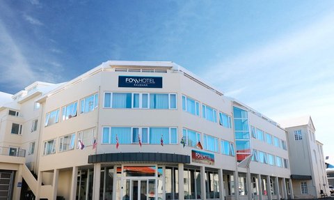 Das Fosshotel Raudara präsentiert sich mit einer modernen Fassade und großen Fenstern unter einem strahlend blauen Himmel.