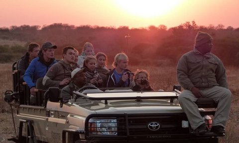 Reisegruppe im offenen Safari-Jeep entdeckt die Tierwelt bei Nacht – Südafrika mit Kindern