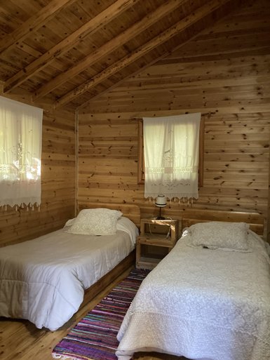 Ein gemütliches Zimmer mit zwei Einzelbetten, Holzvertäfelung und einem bunten Teppich auf dem Boden.