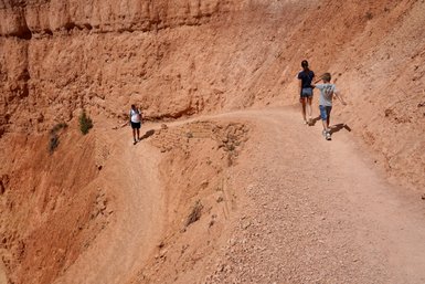 Eine Familie wandert auf einem schmalen Pfad durch die orangefarbenen Felsen des Bryce Canyon Nationalparks.