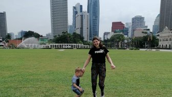 Mutter und Kind springen auf einer grünen Wiese in Kuala Lumpur – Malaysia & Borneo Familienreise