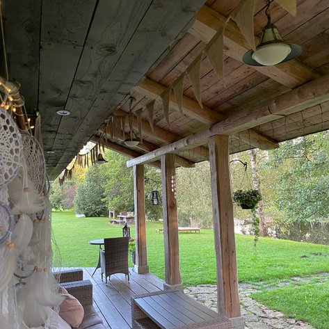 Eine gemütliche Veranda mit Rattanmöbeln und einer schönen Aussicht auf den grünen Garten und den ruhigen Fluss.