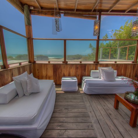 Ein stilvoller Innenraum mit Holzverkleidung, bequemen Sofas und Blick auf das Meer durch große Fenster.