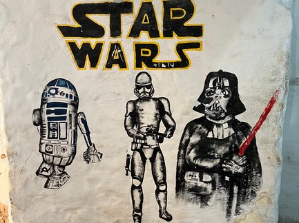 An einer Wand sind berühmte Star Wars Charaktere wie R2-D2, ein Stormtrooper und Darth Vader in lebhaften Farben dargestellt.