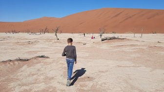 Ein Kind läuft durch eine Wüstenlandschaft - Namibia Reise mit Kindern