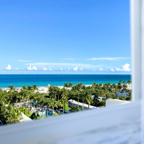 Eine atemberaubende Aussicht auf den blauen Ozean und den weißen Sandstrand, umgeben von tropischen Palmen.