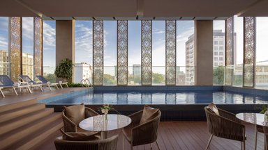 Ein eleganter Innenpool mit blauen Fliesen, umgeben von großen Fenstern und modernen Liegen, die zum Entspannen einladen.