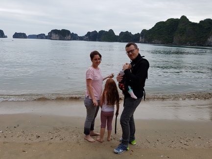 Eine Familie steht am Strand, während sanfte Wellen an den Ufern plätschern, umgeben von beeindruckenden Felsen.