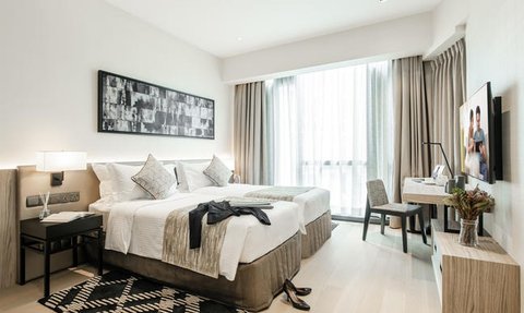 Elegantes Schlafzimmer mit zwei Betten, modernes Design und großen Fenstern, die für viel Tageslicht sorgen.