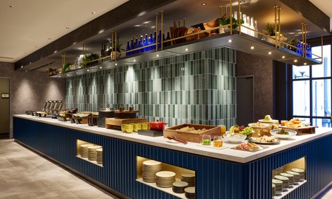 Ein eleganter Buffetbereich mit einer Vielzahl von Speisen, darunter frisches Obst und verschiedene Gerichte, in einem modernen Ambiente.