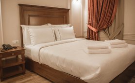 Ein elegantes Hotelzimmer mit einem großen Bett, weißen Kissen und frischen Handtüchern auf der Bettdecke.