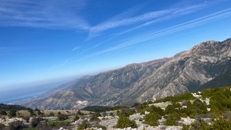 Ein atemberaubender Blick auf die Berge von Llogara Nationalpark, unter einem strahlend blauen Himmel mit sanften Wolken.
