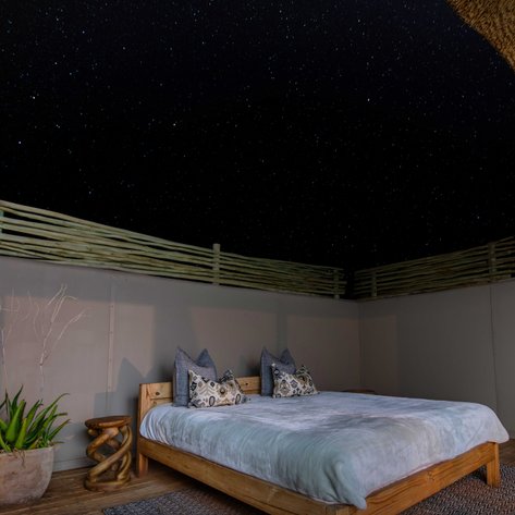 Ein stilvolles Zimmer mit Holzbetten, verdeckt von einem Sternenhimmel, bietet eine ruhige, entspannende Atmosphäre.