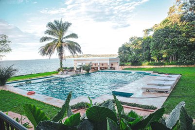 Ein einladender Pool mit klarem Wasser, umgeben von üppigem Grün und einer Palmenlandschaft am Ufer eines Sees.