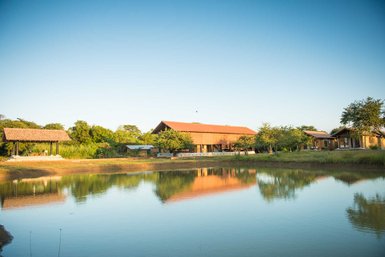Ein ruhiger Blick auf eine Villa in Sri Lanka, umgeben von üppigem Grün und einem glitzernden Teich im Vordergrund.
