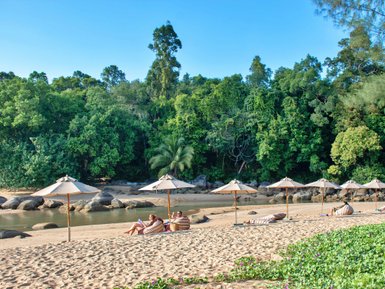 Menschen liegen entspannt am Sandstrand von Khao Lak unter blauem Himmel - Thailand mit Kindern