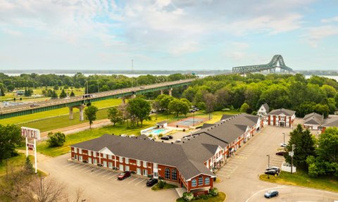 Eine Luftaufnahme eines Hotels mit roten Ziegeln, umgeben von Bäumen und einem großen Parkplatz.