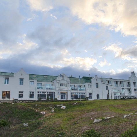 Das elegante Windsor Hotel in Hermanus zeigt eine beeindruckende Fassade mit einem grünen Dach und großen Fenstern.