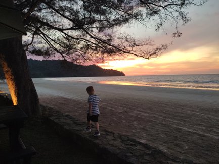 Kind genießt den Sonnenuntergang am Strand des Nexus Resorts – Malaysia & Borneo Reise mit Kindern